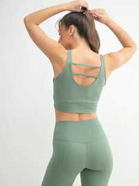 Woman in a green activewear U-back tank top, showcasing the stylish U-back design.