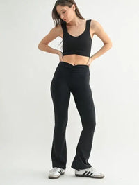 Model wearing a MONO B ruched active tank top and black flared pants, showcasing stylish activewear fashion.