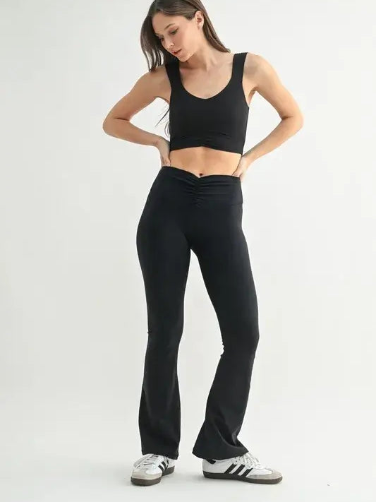 Model wearing a MONO B ruched active tank top and black flared pants, showcasing stylish activewear fashion.
