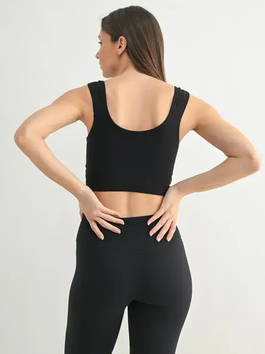 Back view of a woman wearing a black ruched active tank top and leggings, showcasing the stylish design.